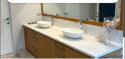 Clean warm wood bathroom vanity with dual basins installed by Mike